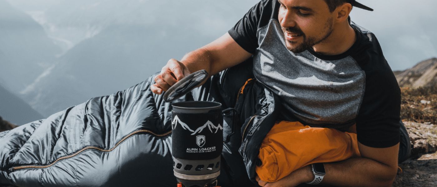 Ein Mann betrachtet ein Vergrößerungsglas, trägt Outdoor-Kleidung und einen Rucksack, passend zum Sortiment von Alpin Loacker.