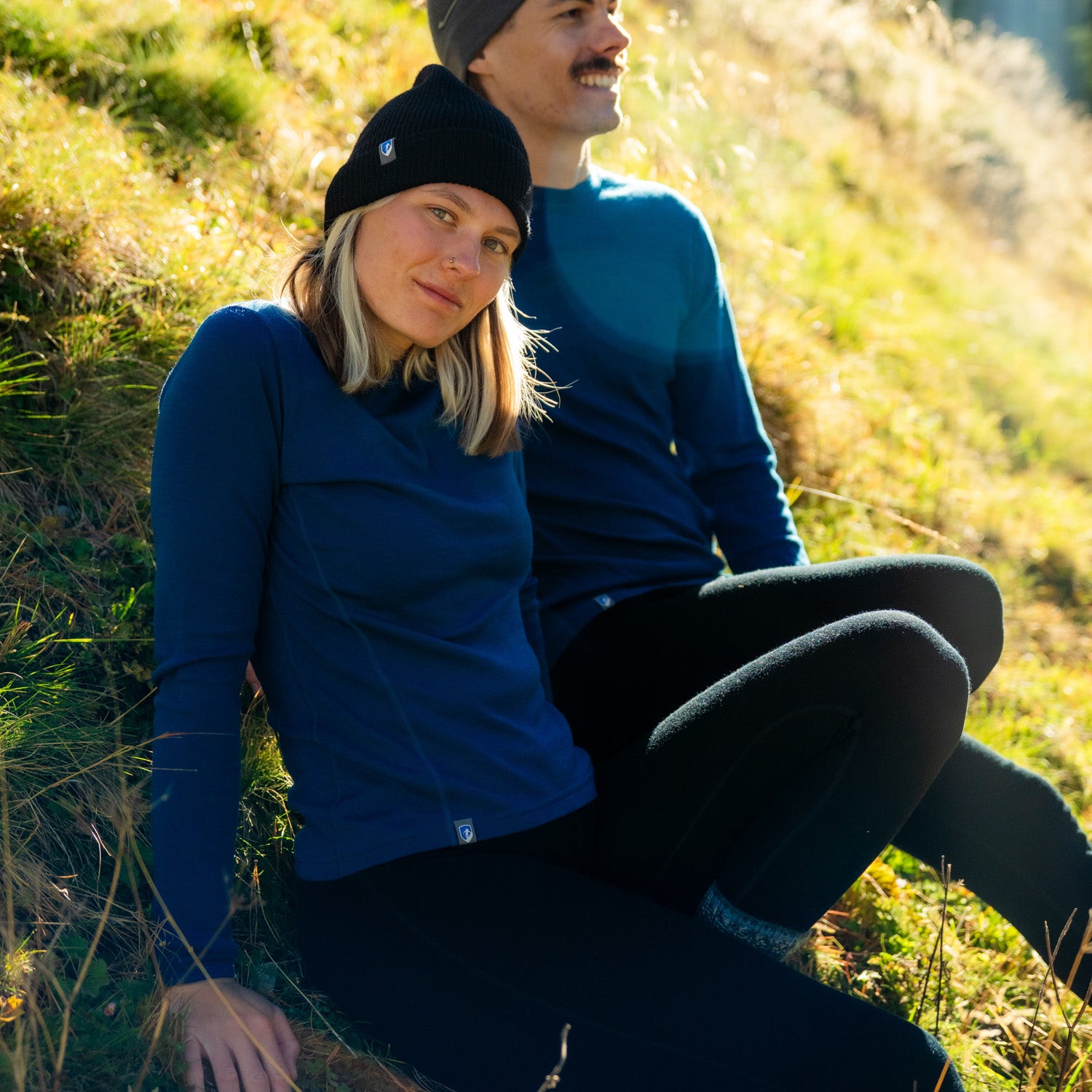 Pärchen sitzt in Meirno Sets in der Natur und genießen den weichen Wollstoff - die perfekte untere Schicht für die kühlere Tage. 