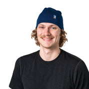 Person trägt eine blaue Merino Mütze Herren & Damen 230g/m² aus 100% Merinowolle, ideal für Outdoor-Aktivitäten, leicht und komfortabel