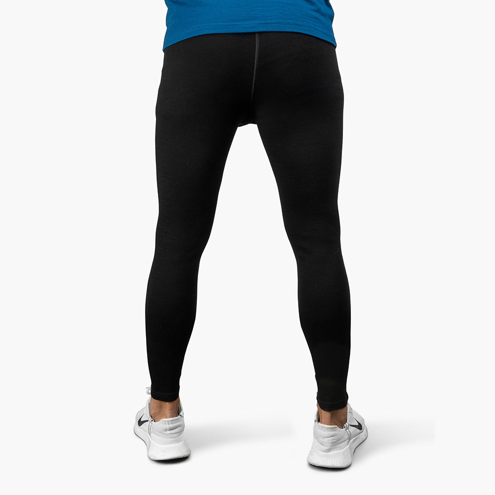 Mann in schwarzen Lange Merino Unterhose Herren 230 g/m2 und weißen Sneakers, ideal für Outdoor-Aktivitäten dank Merinowolle-Komfort und Atmungsaktivität.