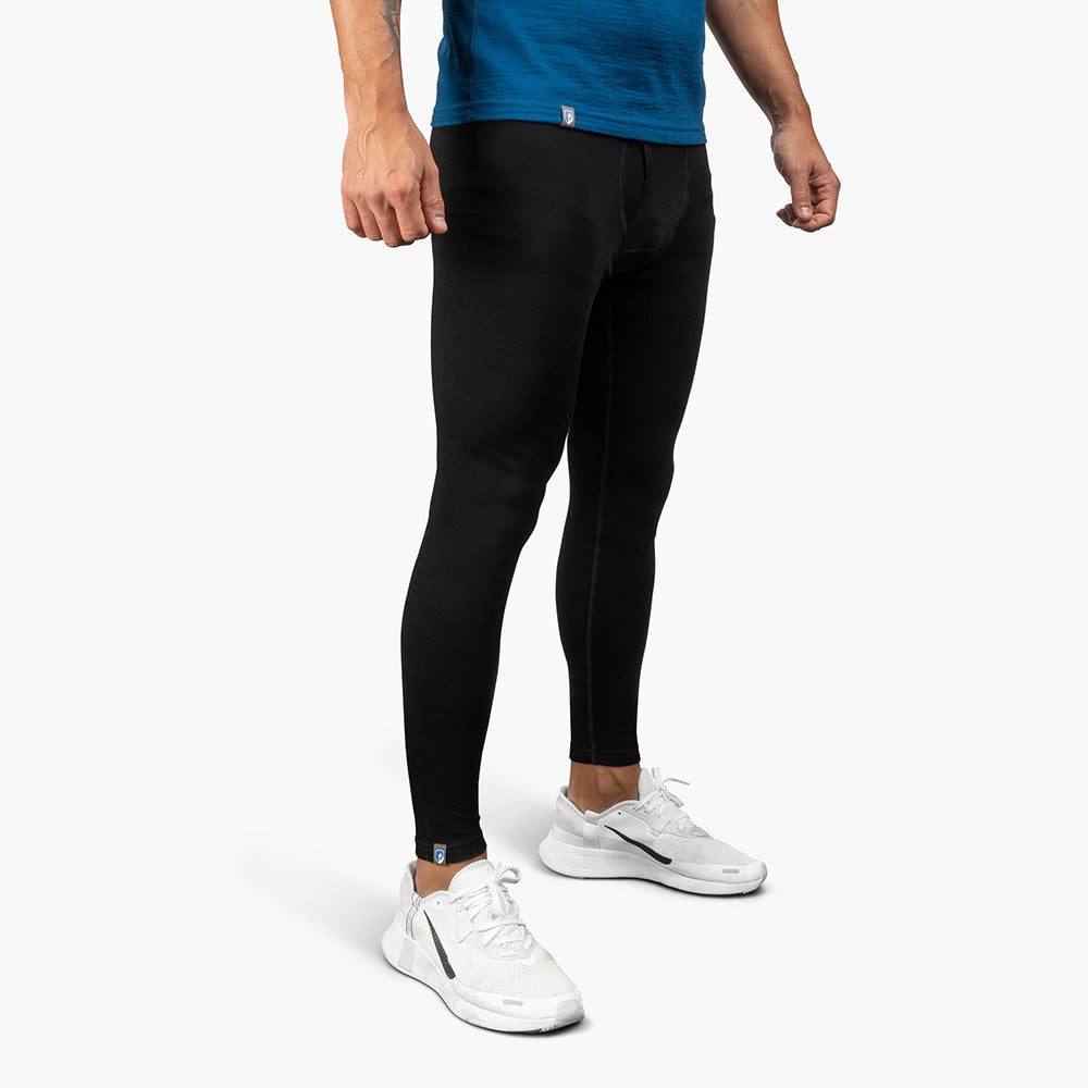 Lange Merino Unterhose Herren 230 g/m² und weiße Sneakers, betont durch blauen Shirtansatz, ideal für Outdoor-Abenteuer dank Komfort und Funktionalität.