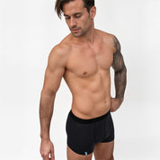 Merino Boxershorts Herren 150 g/m2 modelliert von tätowiertem Mann, betont modernen Komfort und Funktionalität durch CORESPUN-Technologie, ideal für Outdoor-Abenteuer und täglichen Gebrauch.