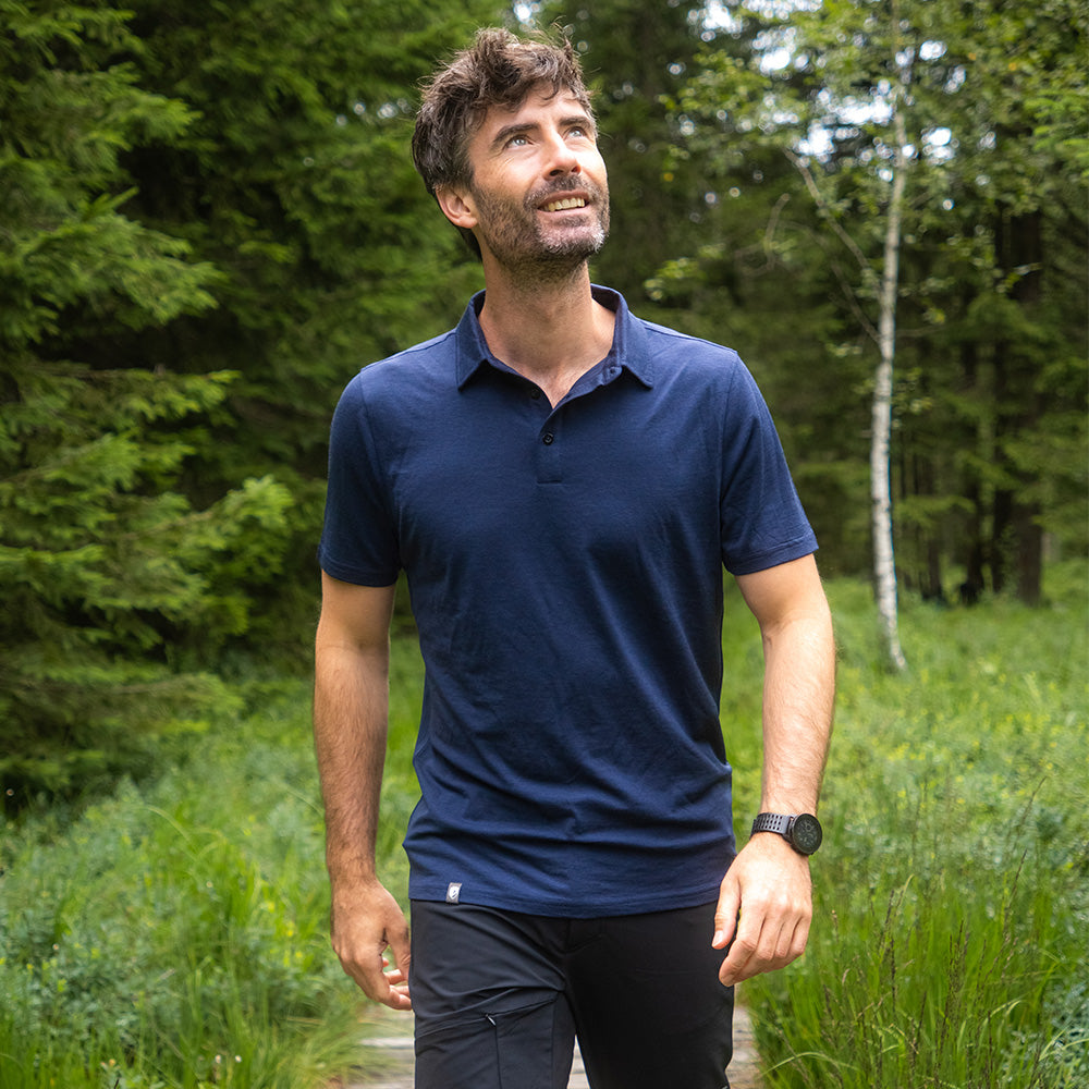 Mann in Merino Polo Shirt Herren auf Waldpfad, genießt Natur. Ideal für Outdoor-Aktivitäten dank atmungsaktiver und temperaturregulierender Merinowolle von alpinloakor.shop.