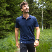 Mann in Merino Polo Shirt Herren auf Waldpfad, genießt Natur. Ideal für Outdoor-Aktivitäten dank atmungsaktiver und temperaturregulierender Merinowolle von alpinloakor.shop.