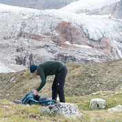 Ein Wanderer in alpiner Umgebung sortiert Ausrüstung, während er die Softshell Wanderhose Herren trägt, ideal für Komfort und Flexibilität auf anspruchsvollen Touren.