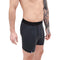 Mann trägt Merino Boxershorts Herren 150 g/m2, dunkle Mid-Length Boxer-Briefs mit Logo-Tag, ideal für Outdoor-Aktivitäten, sportliche und tägliche Nutzung.